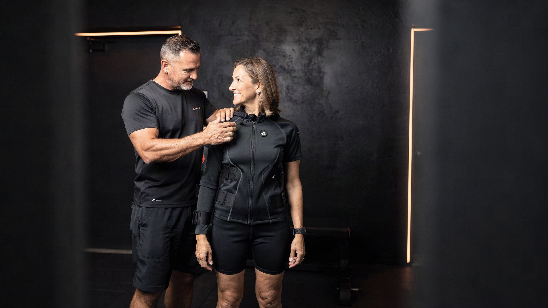 A trainer and a member at the start of a session in a small dark studio