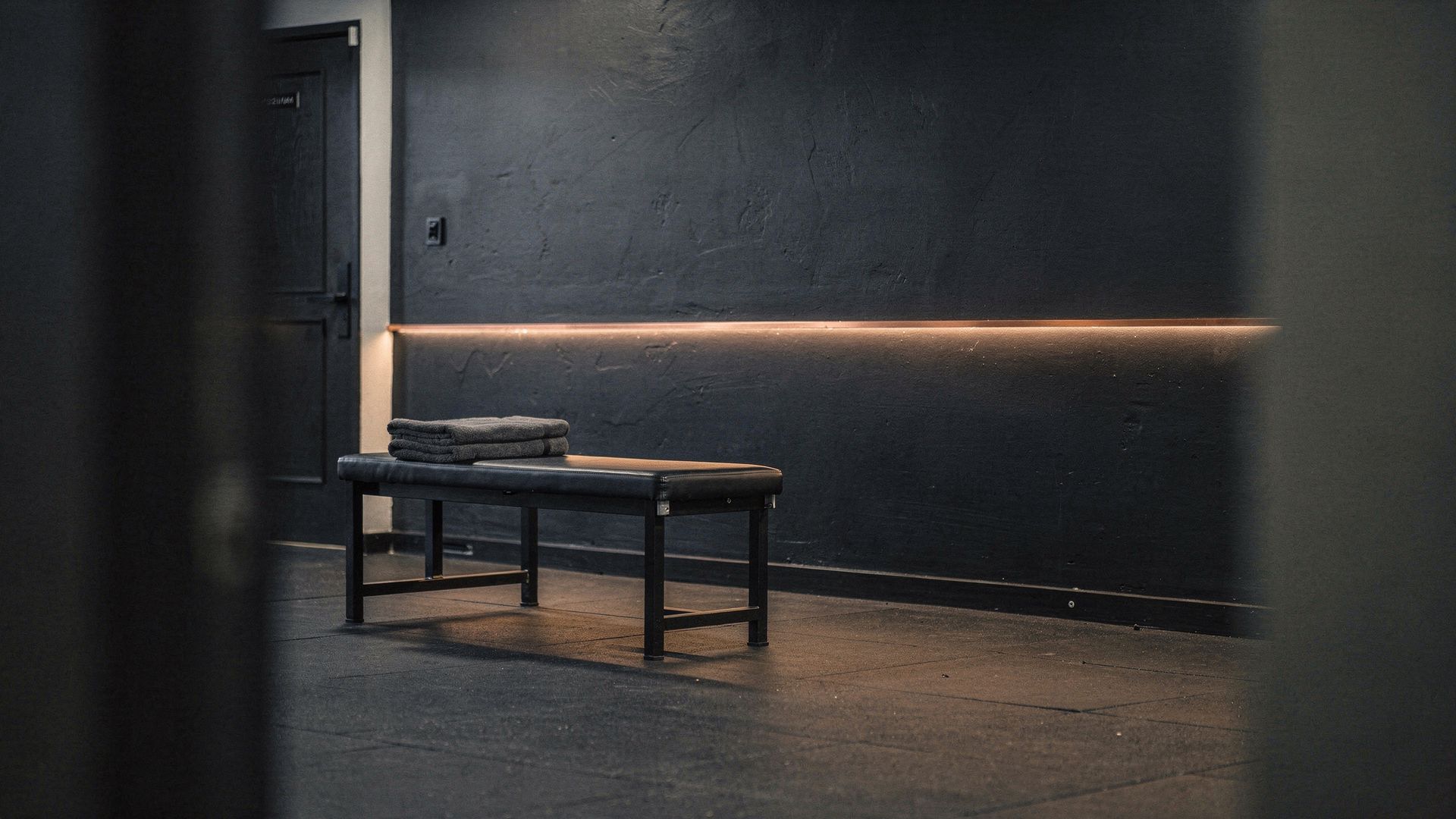 An empty training room with one bench and a warm light line, ready for the next appointment