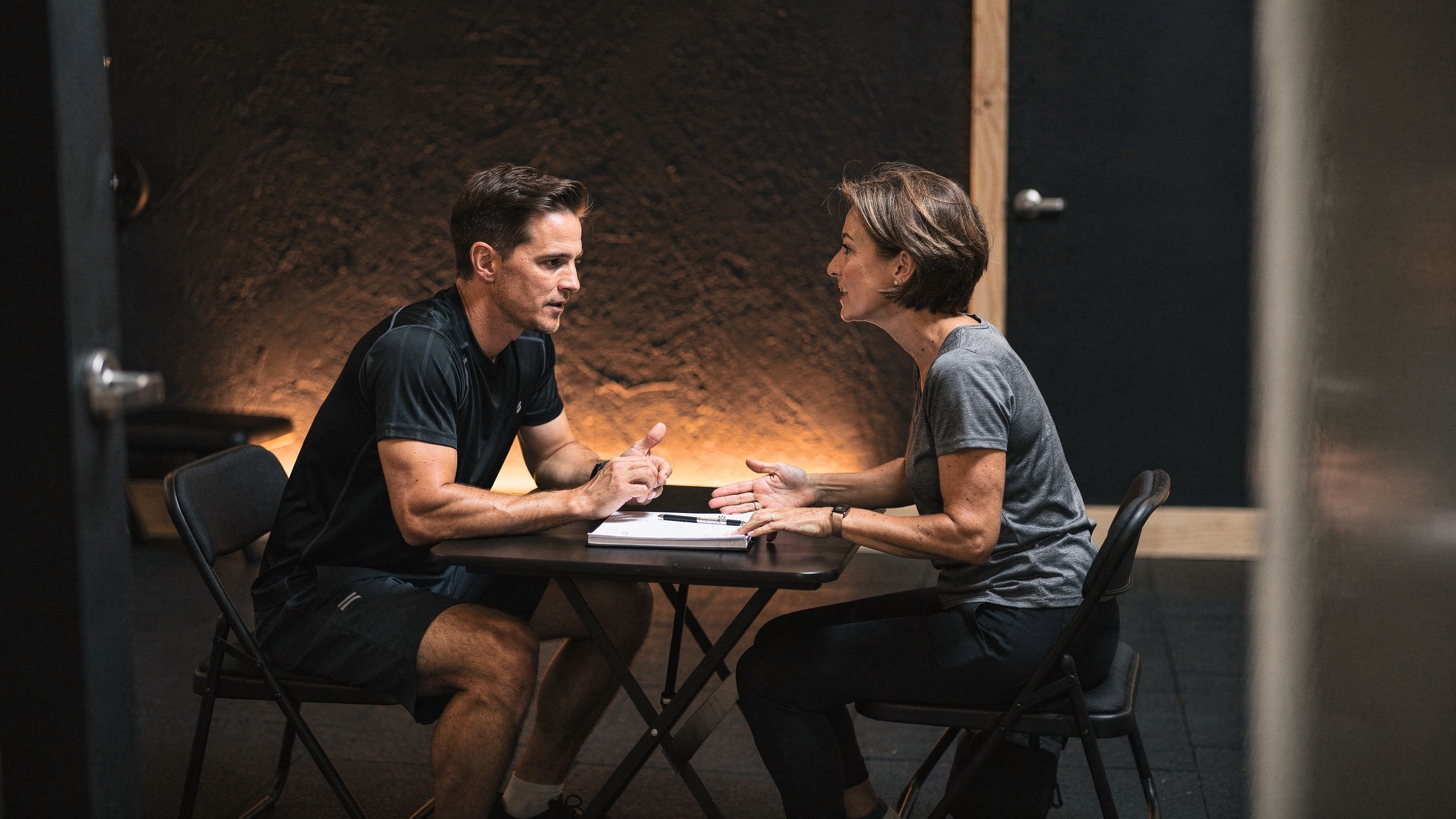 A trainer and a member talking at a small table